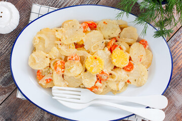 Baked potatoes with carrots in the oven on a white dish, selective focus