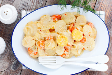 Baked potatoes with carrots in the oven on a white dish, selective focus