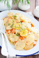 Baked potatoes with carrots in the oven on a white dish, selective focus