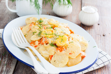 Baked potatoes with carrots in the oven on a white dish, selective focus