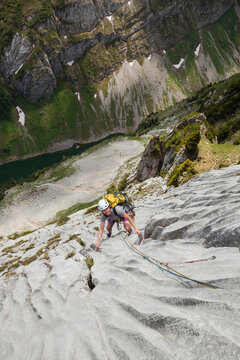 Woman rock climbs limestone cliff in Alpstein, Appenzell, Switzerland