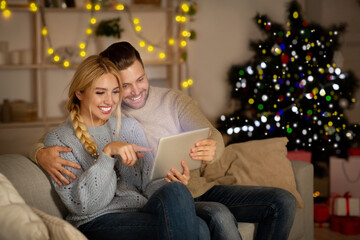 Joyful couple playing games together at home on digital tablet