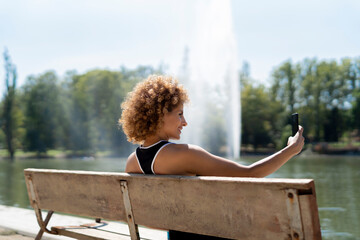 woman on a bench by the lake taking a selfie