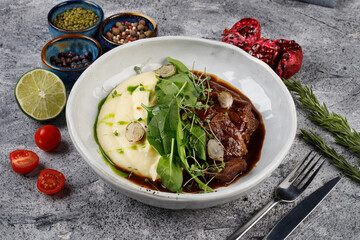 Veal cheeks in gravy with potatoes and cabbage, decorated with herbs