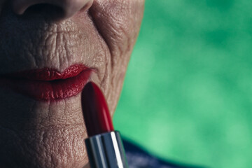 Elderly woman with lipstick and red painted lips in green background