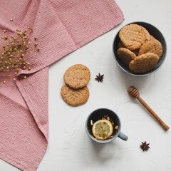 Cup of black tea, lemon, homemade cookies and tablecloth on white rustic  background. Breakfast concept. Top view, flat lay style