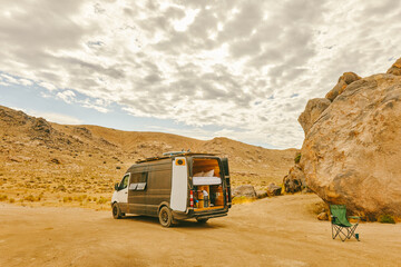 Camper van parked in desert near foothills in northern California.