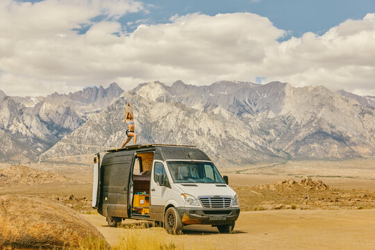 Woman practicing yoga on roof of camper van in northern California.