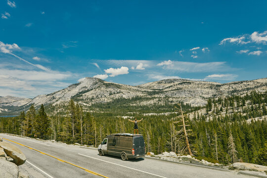 Young man standing on camper van watching views of Yosemite Park.