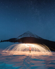 Fire show with lot of sparks in night winter mountains. Landscape photography