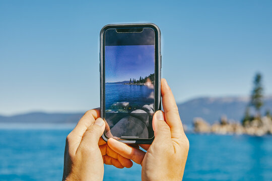 Young woman taking a picture of Lake Tahoe.