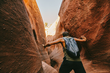 Young man exploring narrow slot canyons in Escalante, during summer
