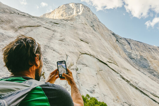 Young man taking picture of El Capitan Mountain in Yosemite Park.