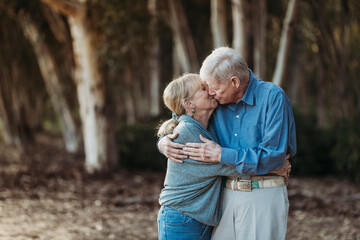 Portrait of senior adult retired couple kissing in forest