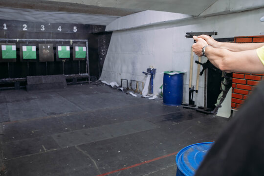 Shooting range. Rear view of men shooting with gun in shooting range