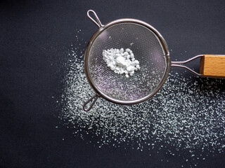sieving icing sugar on black background 