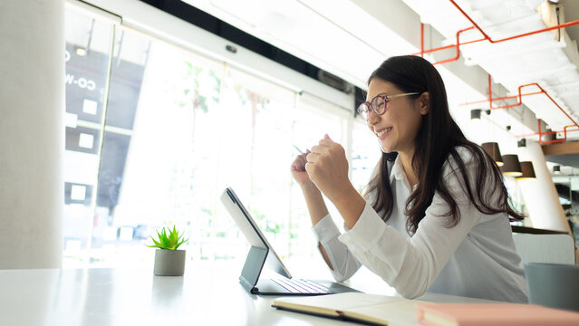 Portrait of cheerful female office worker celebrating while working in office