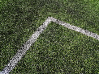 White line on the green grass of sporting stadium. Artificial sports surface green grass imitation on the football stadium
