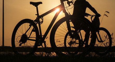 A silhouette of a bike at sunset. The sun shines through the bicycle frame, selective focus