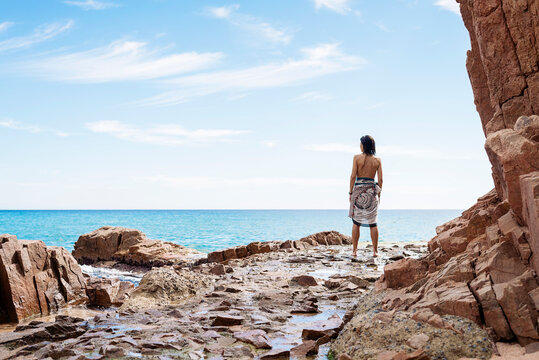 Rear view of a woman standing on seashore, looking to horizon