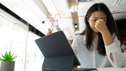 Portrait of female office worker feeling tried while working with tablet in office