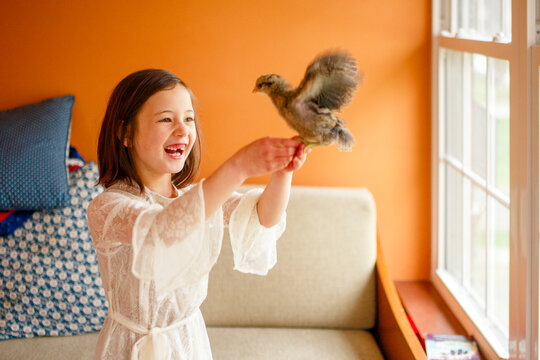 Smiling girl with missing tooth playing with pet bird at home