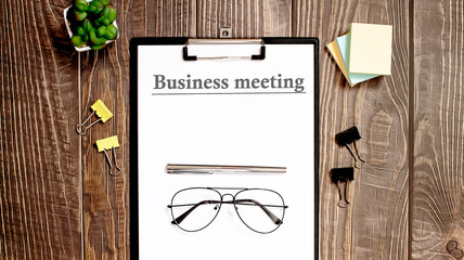 Business reports, blank paper sheet - directly above view of office table workspace with BUSINESS MEETING text.
