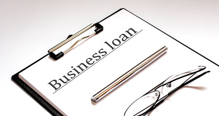 BUSINESS LOAN Concept on white sheet with pen and glasses