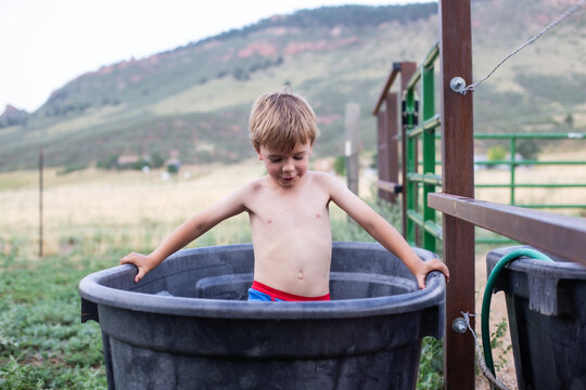 Small boy standing in his underwear in a horse trough