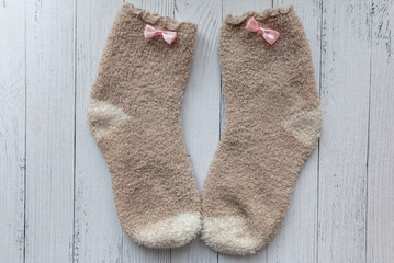 Fototapeta na wymiar pair of beige socks with pink ribbon isolated on wooden background. Warm clothing