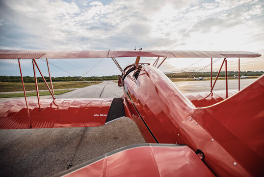 Red shiny restored vintage airplane on airfield at sunrise in Maine