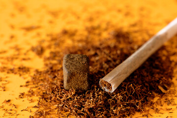 Block of hashish, with cigar a concentrate of medical marijuana on top of tobacco background in yellow