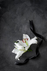 Funeral symbols. White lily with black ribbon, top view