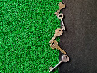Set of different sizes of house keys or shop keys in zig zag position. Isolated on black and green...