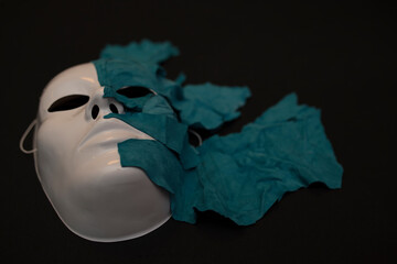 White theater mask on a black background covered with leather flaps. Psychic symbol of overlapping layers.