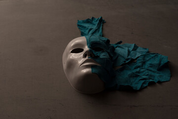 White theater mask on a black background covered with leather flaps. Psychic symbol of overlapping...