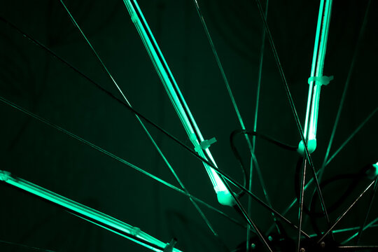 The Spokes On The Bike Shine Are Green Light On Black Background. Green Light Close Up. Wallpaper