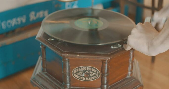 Man is putting a vinyl record pn gramophone.