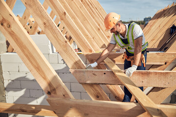 Professional builder in protective equipment building a roof