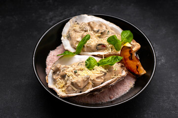 Rapana meat in a creamy cheese sauce in a shell, on a plate, on a dark background