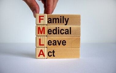 Concept words 'FMLA, family medical leave act' on cubes and blocks on a beautiful white background. Male hand. Copy space. Medical concept.