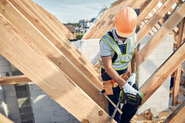 Fototapeta premium Professional builder in a hard hat working with a chainsaw