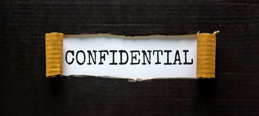 The word 'confidential' appearing behind torn black paper. Business concept.