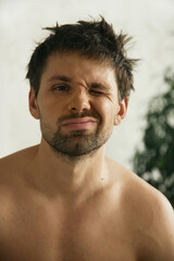 Fototapeta premium European man in his flat. Sitting in the living room. Bronze skin. Dark eyes and hair. Beard. Light colored interior. Casual clothes style. Weekend at home. Domestic atmosphere. Cosiness and comfort