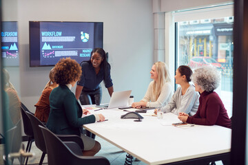 Young Businesswoman Leading Creative Meeting Of Women Collaborating Around Table In Modern Office