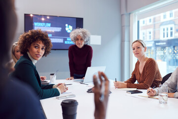 Mature Businesswoman Leading Creative Meeting Of Women Collaborating Around Table In Modern Office