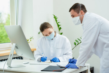 A surgeon and a radiologist in medical masks discuss a diagnosis of a patient.