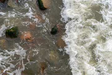 Rocks on the beach are washed by the sea wave.