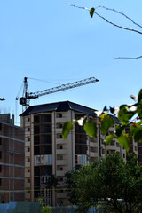 View of unfinished houses and a crane above them on a clear autumn day.