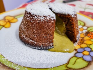 Tortino al cioccolato con cuore caldo al pistacchio decorato con zucchero a velo